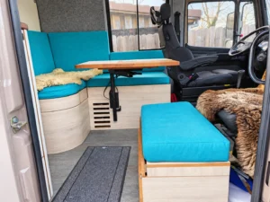 Maßgefertigte Sitzgruppe mit Holztisch, Stauraum und türkisfarbenen Polstern.